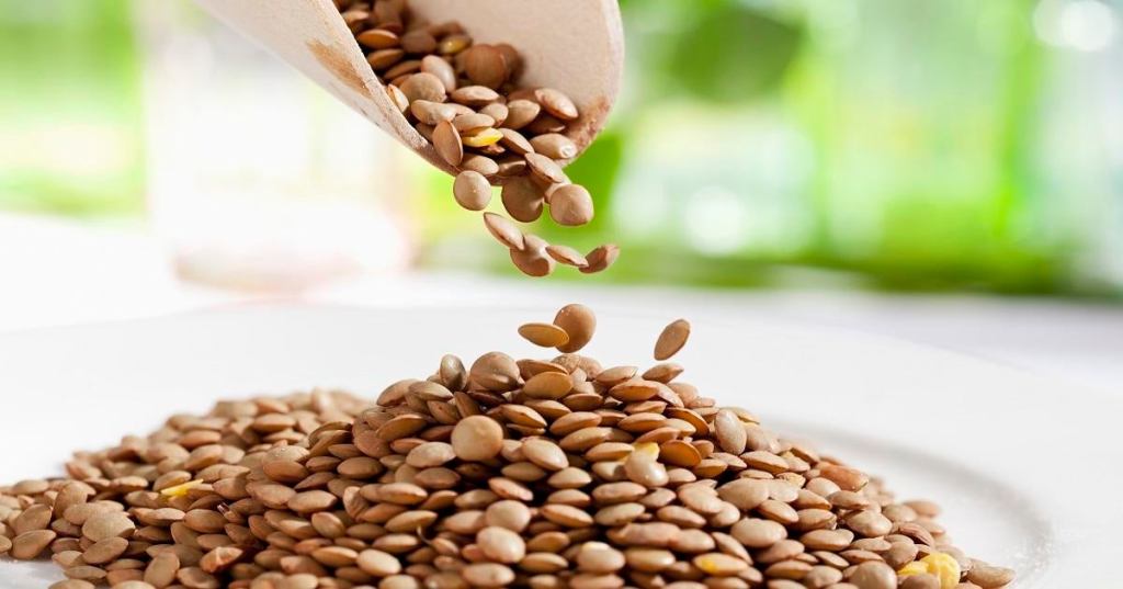 Lentils pouring from wooden scoop, close up