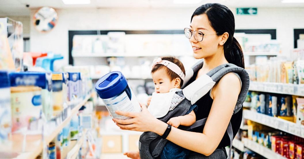 mother-carrying-baby-girl-looking-at-baby-formula.jpg