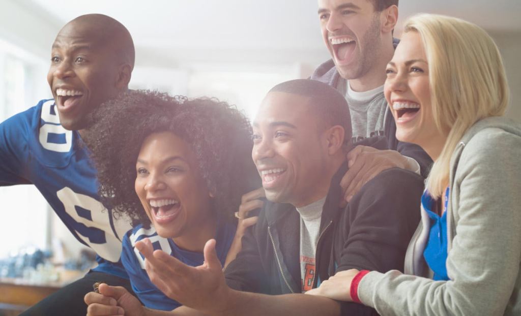 Friends drinking beer and cheering at game on television