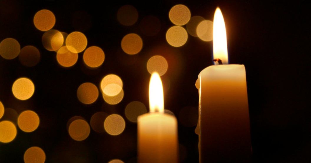 Candles burning in front of out of focus lights