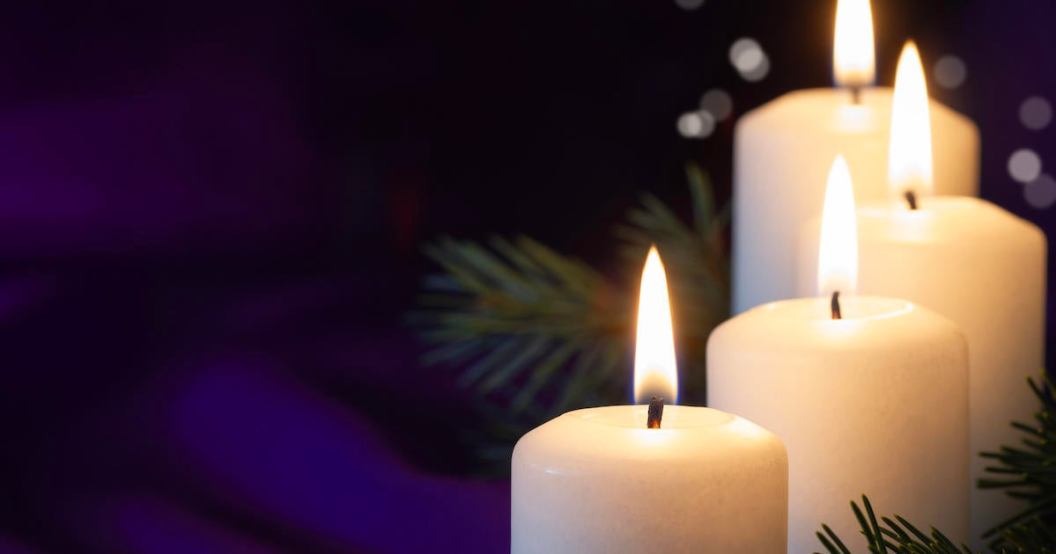 Four burning Advent candles with spruce twigs on purple background, religious symbol, copy space